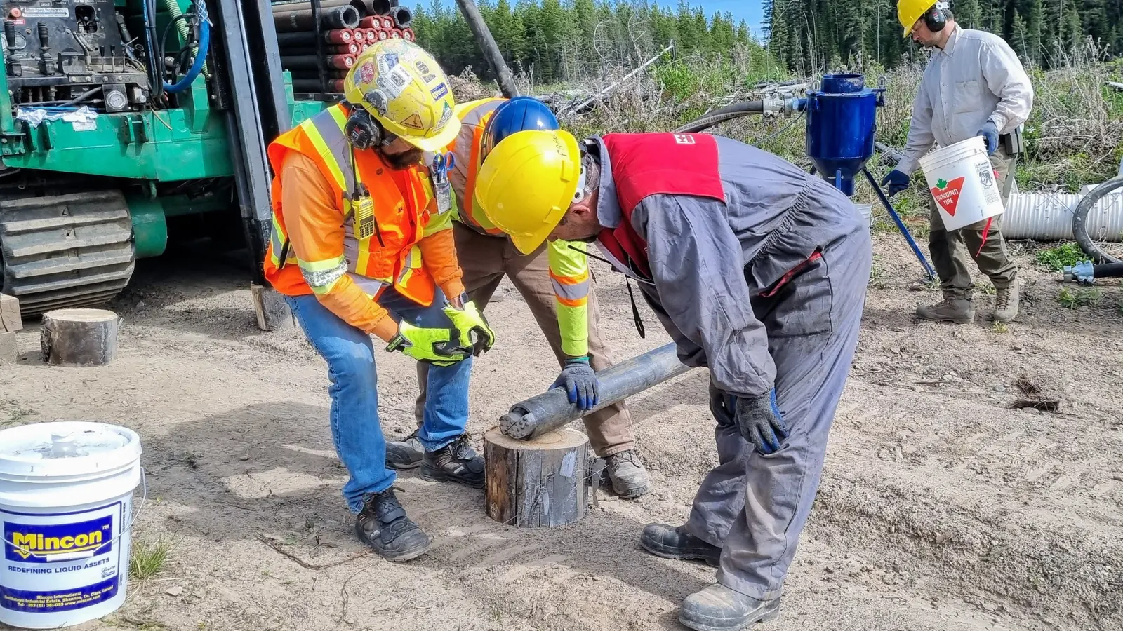 Crew examining a drill sample on a stump at an exploration site